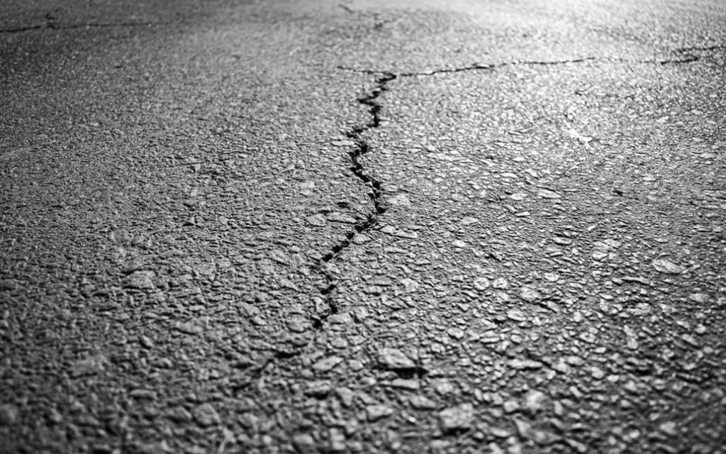 Traffic on a cracked asphalt road posing challenges to infrastructure