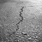 Traffic on a cracked asphalt road posing challenges to infrastructure
