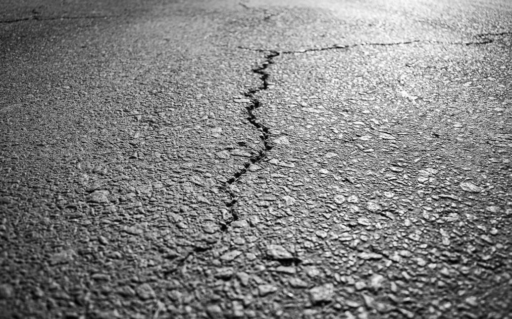 Traffic on a cracked asphalt road posing challenges to infrastructure