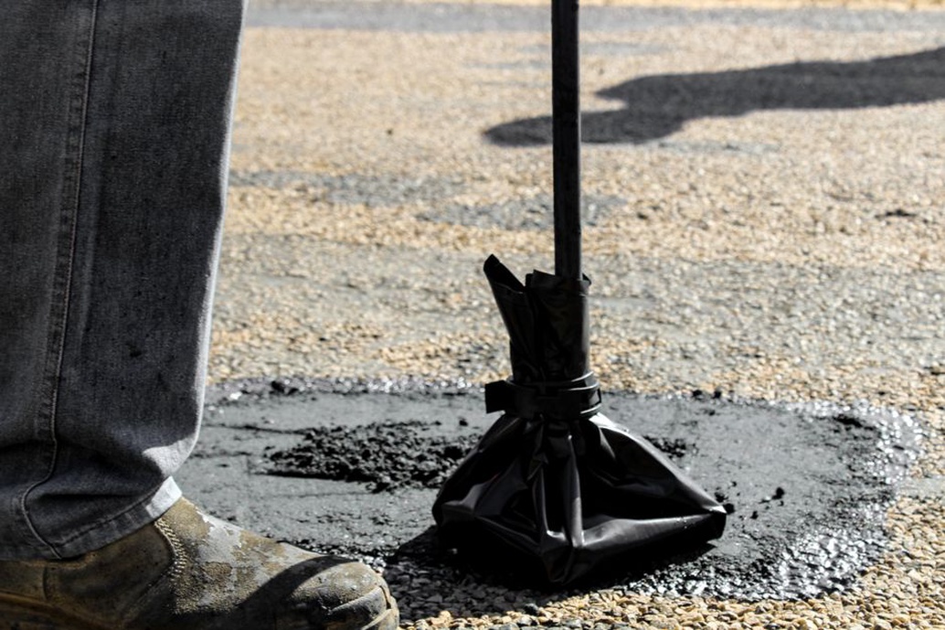Workers in reflective vests repairing potholes on a busy road