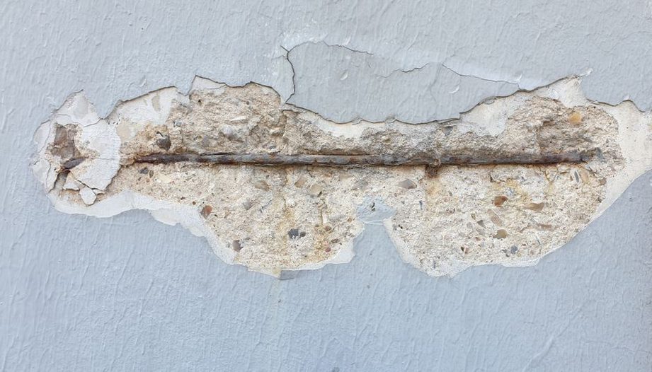 Engineer documenting concrete cracking near bridge reinforcement