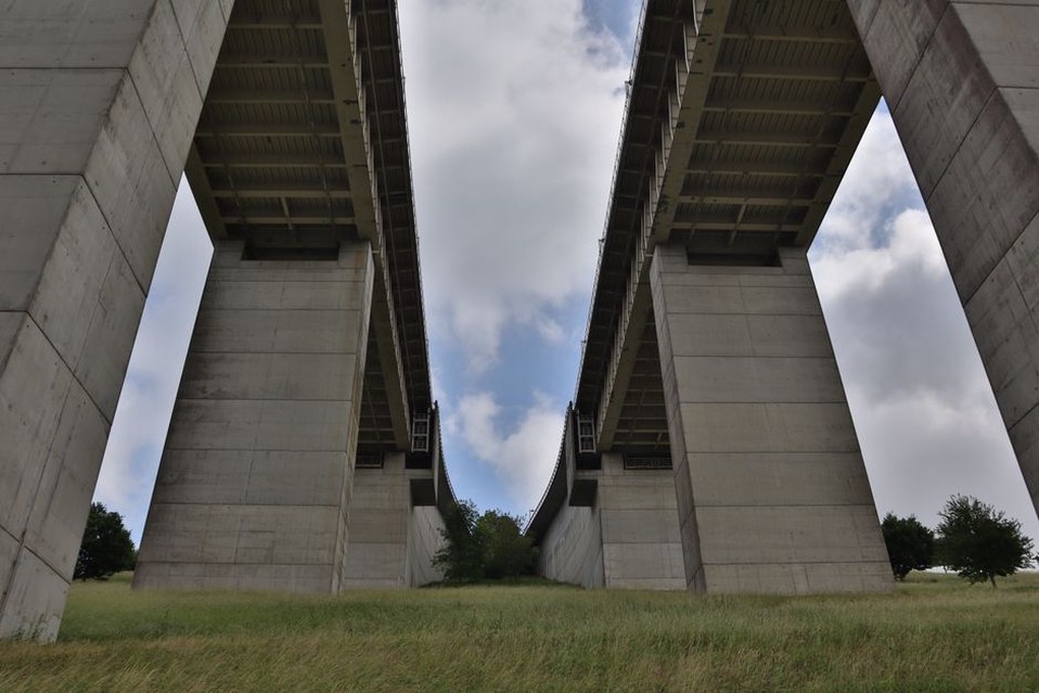 Inspector examining accessible components beneath a bridge deck