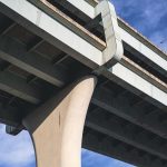 Engineer documenting defects beneath a concrete bridge