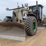 A bulldozer compacts soil at a highway construction site