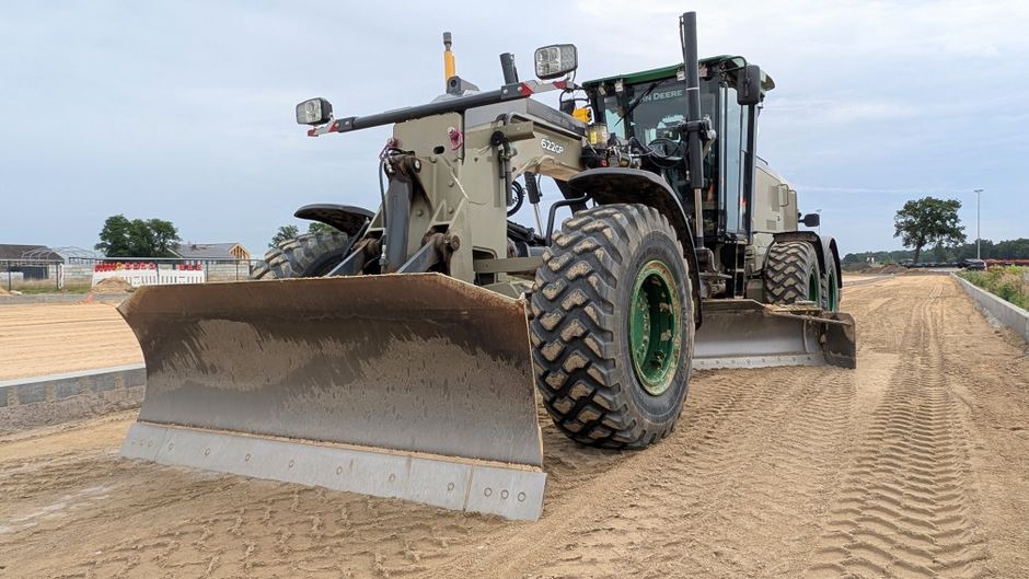 A bulldozer compacts soil at a highway construction site