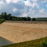 Engineer inspecting erosion beside a flooded rail embankment