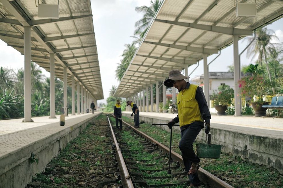 Workers inspect drainage beside an older rail line