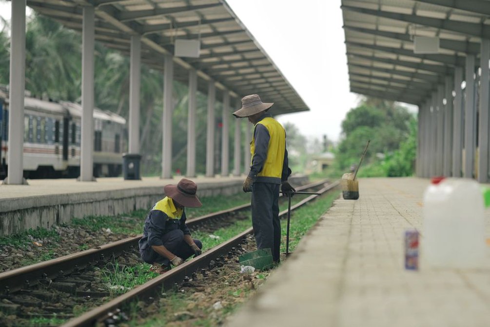 Workers checking track alignment beside railway sleepers