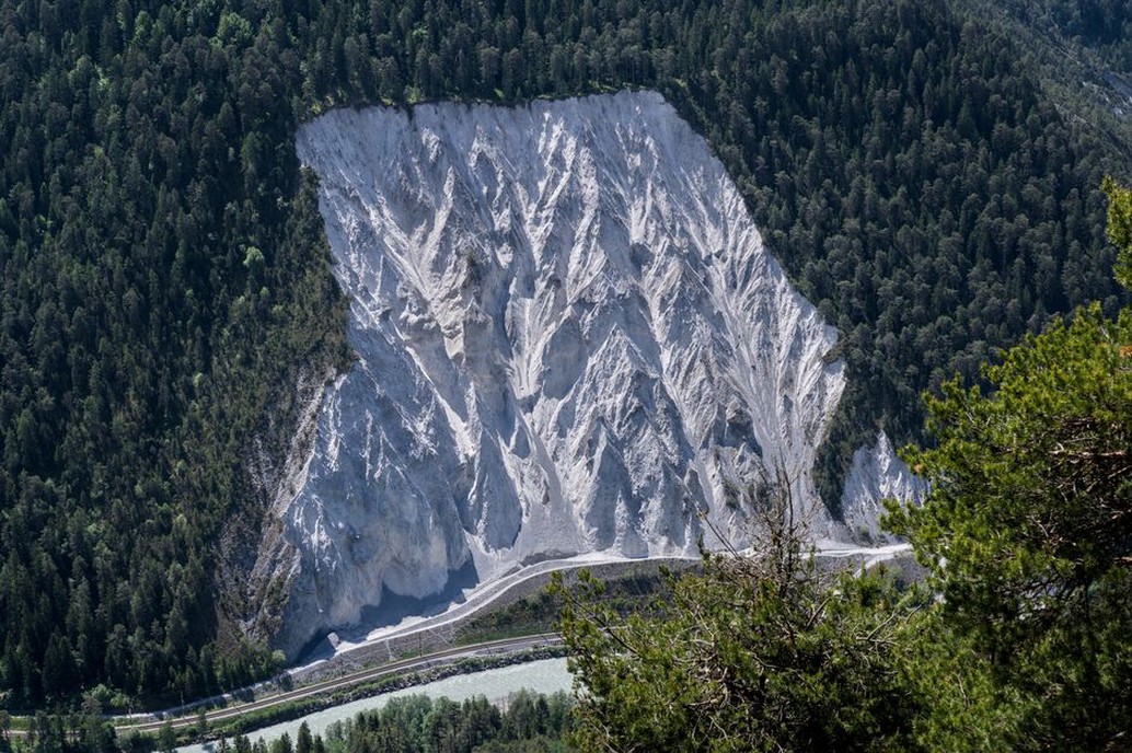 A catch fence separates a steep slope from railway tracks