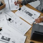 Engineer checks a technical document beside a laptop