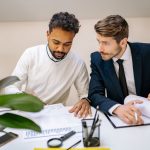 Technical team comparing project records around a table
