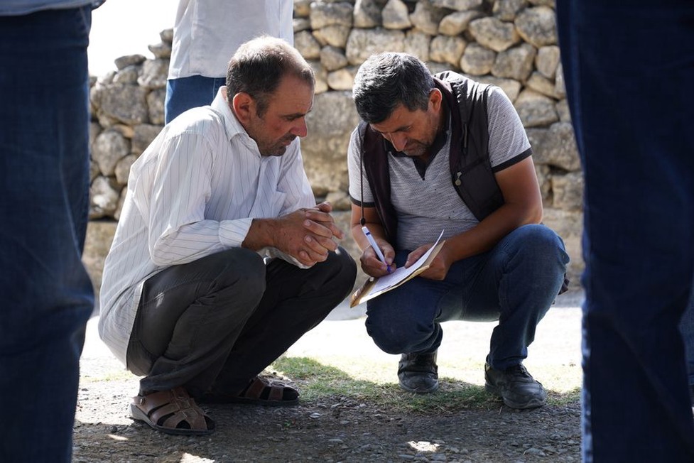 Engineers compare survey records beside a rail embankment